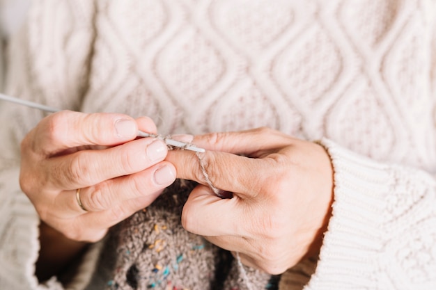 Free photo old woman in sweater knitting scarf