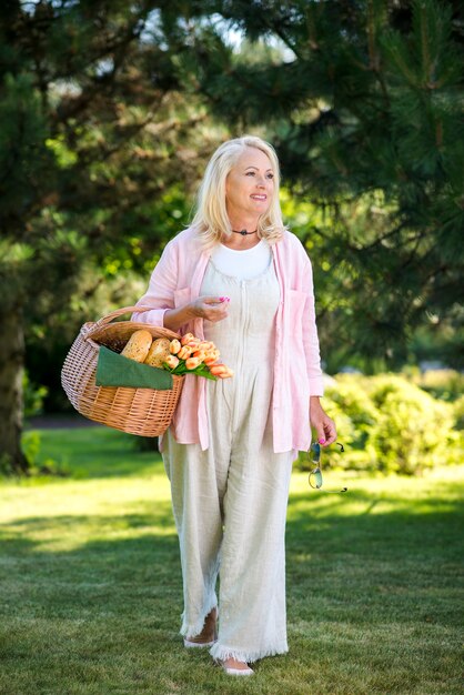 Old woman with a basket walking on meadow