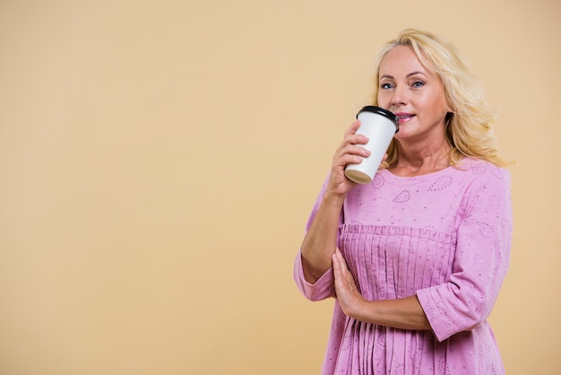 Donna anziana con una tazza di caffè guardando la telecamera