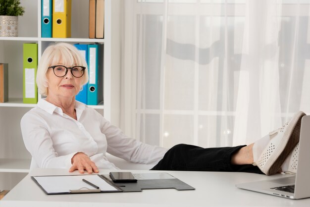 Old woman with eyeglasses sitting in her office