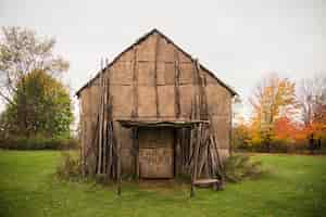 Free photo old wooden barn surrounded by trees in a field under a cloudy sky at daytime