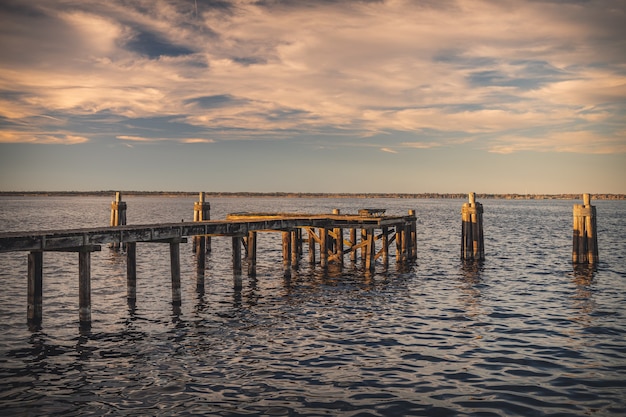 Бесплатное фото Старый деревянный причал на берегу моря под солнечным светом во время заката