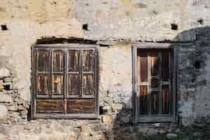 Foto gratuita vecchie porte e persiane in legno sul muro di una casa abbandonata il concetto di sfondo e arredamento l'idea del turismo e lo studio della storia del viaggio