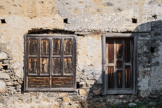 Old wooden doors and shutters on the wall of an abandoned house the concept of background and decor the idea of tourism and travel history study