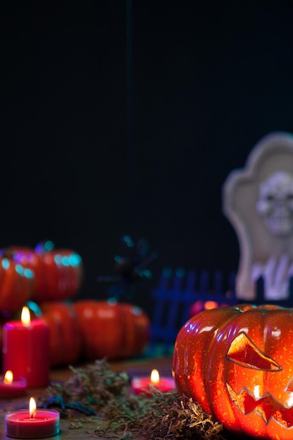 Old wooden table full with scary halloween decorations. Spooky pumpkin. Halloween mortuary stone.