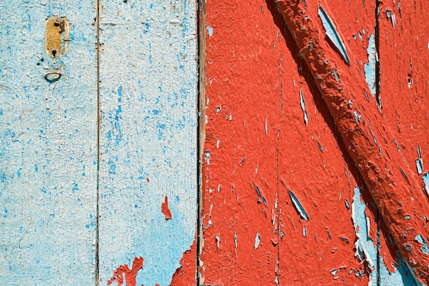 デザインやソーシャルメディアの背景に赤と青のペンキをはがしている古い木製の壁