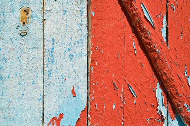 デザインやソーシャルメディアの背景に赤と青のペンキをはがしている古い木製の壁
