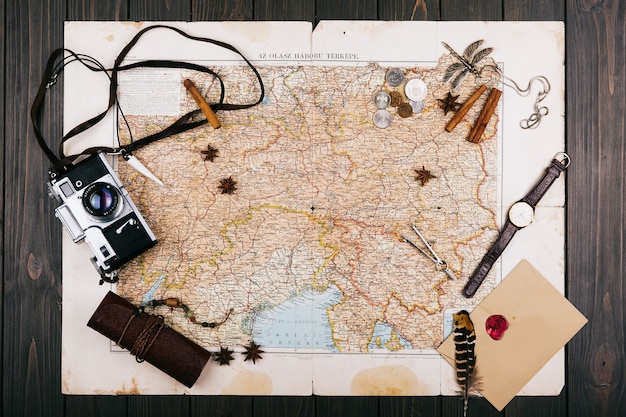 Free photo old yellow map, glasses, coins, leather case, camera, watch, compasses, coffee beans, other spices and cookies lie on wooden floor