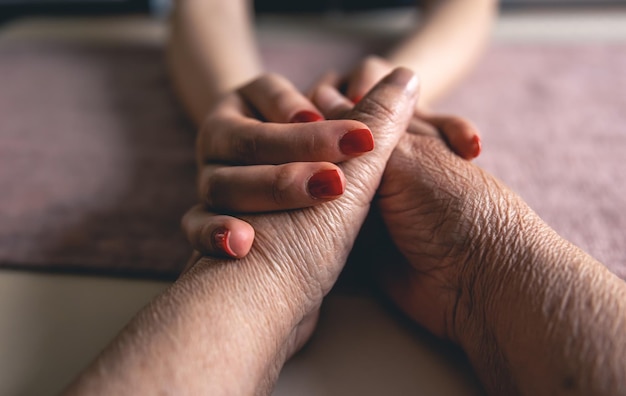 Free photo old and young man holding hands close up