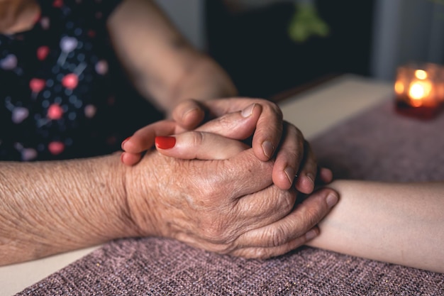 Free photo old and young man holding hands close up