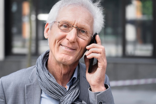 Пожилой случайный мужчина в городе разговаривает по смартфону