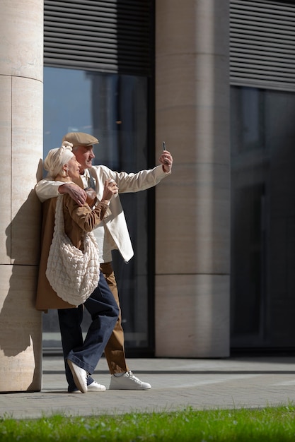 Older couple outdoors in the city having coffee and taking a selfie