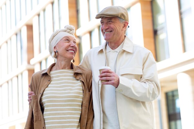 Older couple outdoors in the city with a cup of coffee