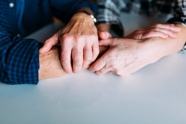 Пожилые пары в отставке дома, держась за руки