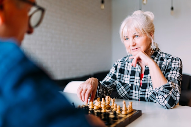 Пожилые пары в отставке дома, играя в шахматы