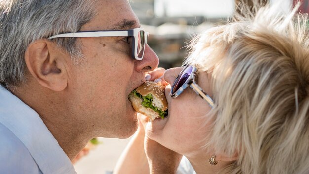 Older couple sharing a burger outdoors