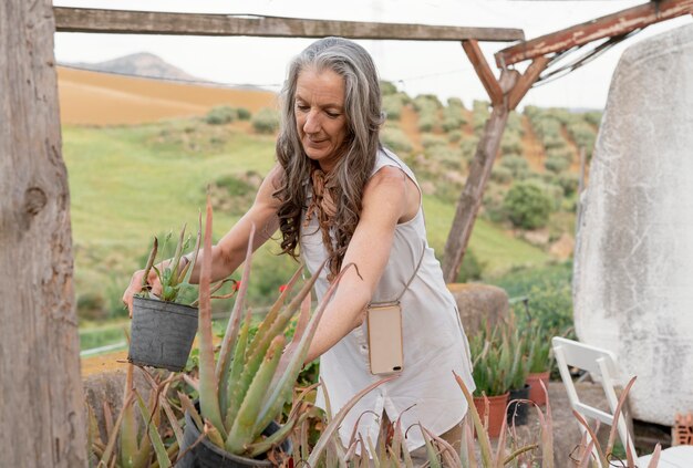 彼女の植物に水をまく年上の女性農夫