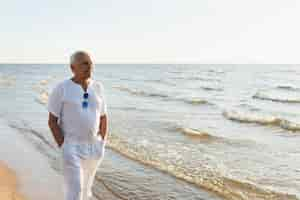 Free photo older man enjoying the view while walking on the beach