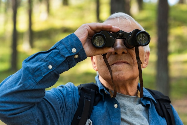 Foto gratuita uomo più anziano che esplora la natura con il binocolo