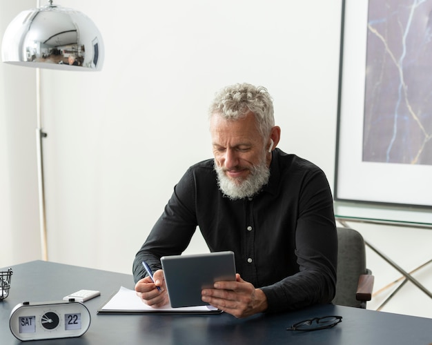 Free photo older man at home using tablet device