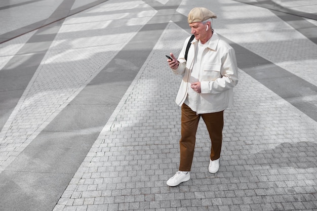 イヤフォン付きのスマートフォンを使用して街の屋外で年配の男性