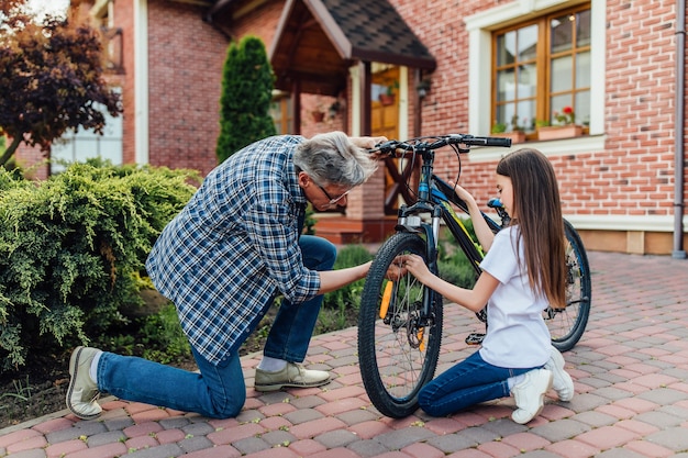 彼の子供のために自転車を修理する年配の男性。ホームタイム、休憩のコンセプト。