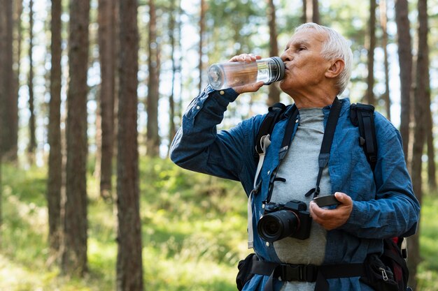 Пожилой мужчина остается гидратированным во время путешествия на свежем воздухе