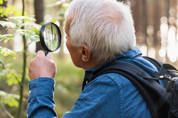 Older man traveling outdoors and using magnifying glass