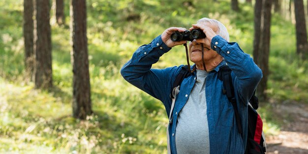 Older man using binoculars while exploring nature