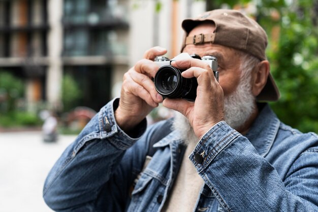 Пожилой мужчина использует камеру на улице в городе, чтобы делать фотографии