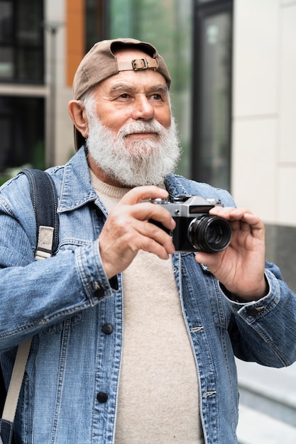 Uomo anziano che usa la fotocamera all'aperto in città per scattare foto