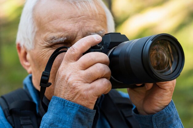 Пожилой мужчина с камерой на открытом воздухе на природе