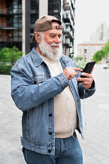 Older man with smartphone outdoors in the city