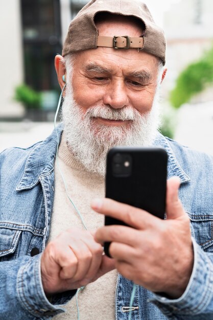 Uomo anziano con smartphone all'aperto in città