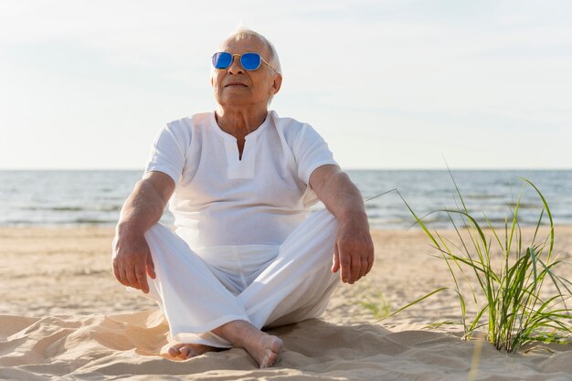 Older man with sunglasses resting on the beach