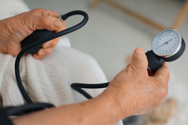 Пожилой человек проверяет свое кровяное давление с помощью тензиометра