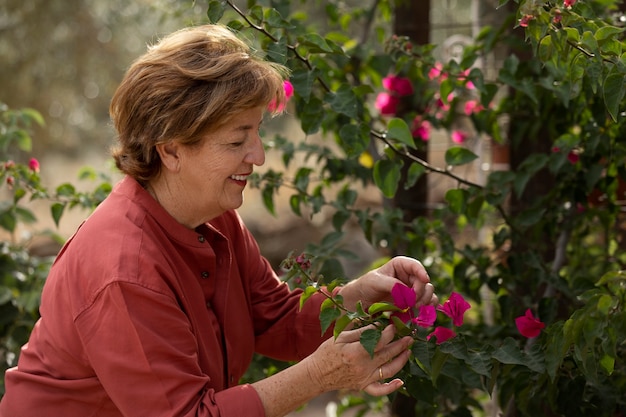 Пожилая женщина наслаждается природой в своем загородном домашнем саду