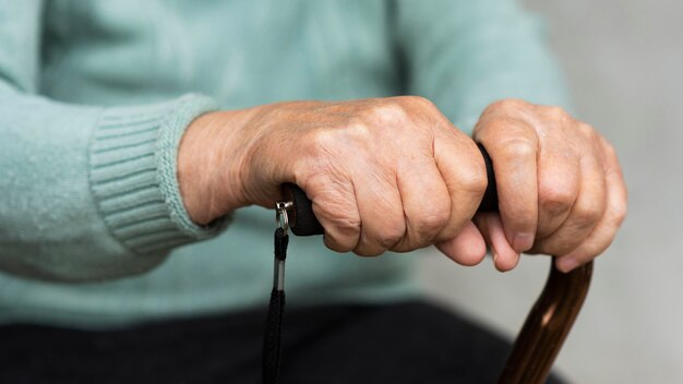 Older woman holding cane in hands