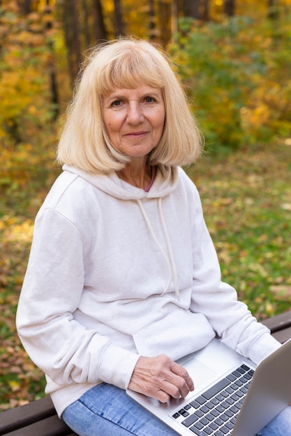 Older woman outdoors in nature with laptop