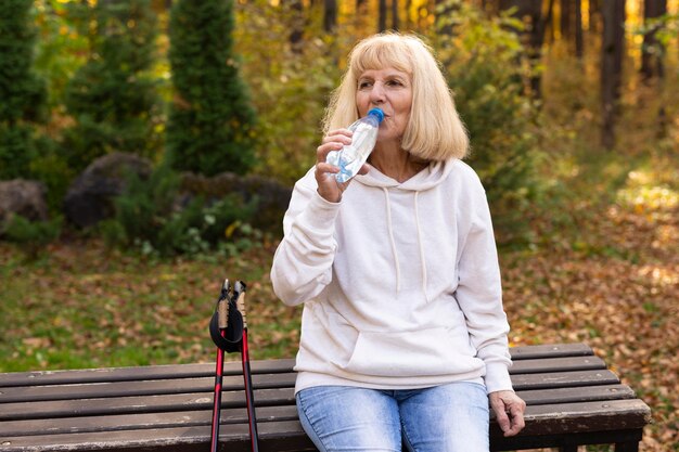 Older woman outdoors trekking and drinking water