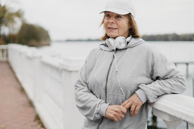 Older woman posing outdoors with headphones