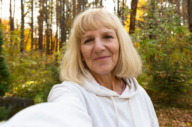 Donna anziana che prende un selfie all'aperto nella natura