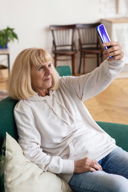 自宅でスマートフォンで自分撮りをしている年上の女性