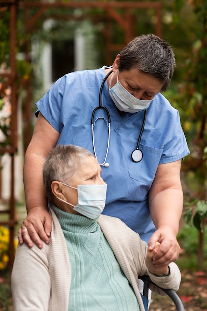 Бесплатное фото Пожилая женщина с медицинской маской и медсестра