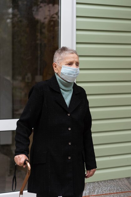 杖を運ぶ医療マスクを持つ年上の女性