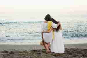 Free photo older women admiring the ocean together while embraced at the beach