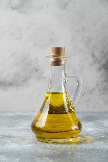 Бутылка оливкового масла на мраморном столе.
