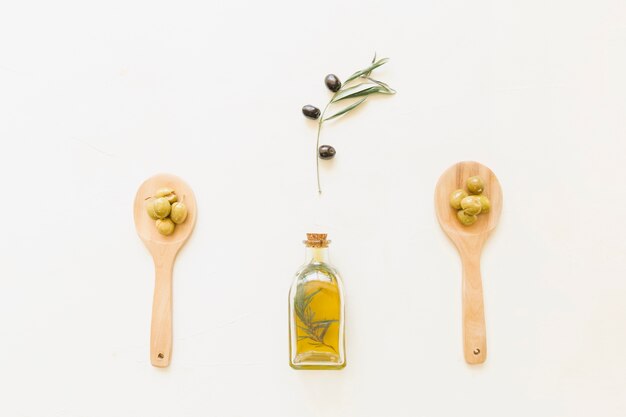 Olive oil in bottle and spoons with olives