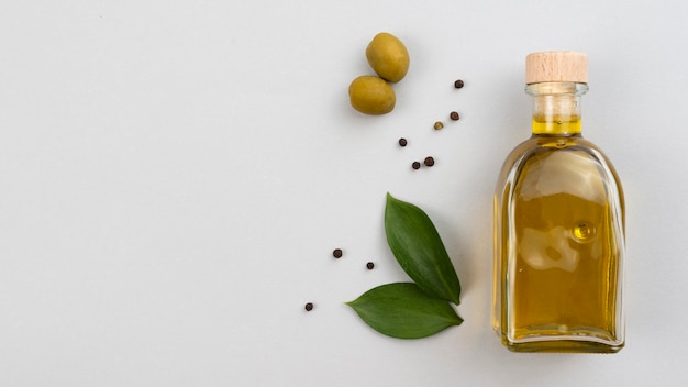 Olive oil bottle with leaves and olives on table