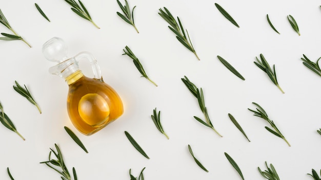 Bottiglia di olio d'oliva con foglie accanto sul tavolo
